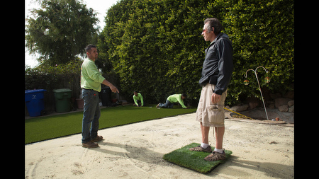 Waterless Turf owner Vic Watterson, right, talks to Jose Sanchez while they install an artificial lawn at a home in Santa Monica, Calif. on Tuesday Feb 11. Watterson estimates his call volume 'has increased around 30 percent' in 2014 due to drought and concerns about water rationing.