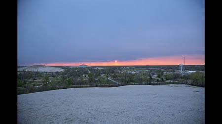 The sun sets over an empty neighborhood in Picher, Okla., a nearly deserted town that once had a population of over 14,000 people in the 1920s, when it was the world's largest producer of zinc and lead. At left and in the foreground are some of the area's many 'chat piles'- heaps of gravelly mine waste. High levels of lead in schoolchildren drove some locals to seek relocation assistance from the government and in 2006, risk of collapsing mines led the federal government to offer property buyouts.