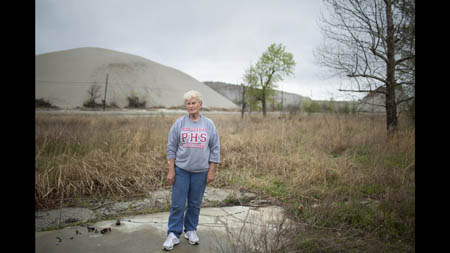 'If it wasn't for the tornado I wouldn't have left,' said Kathy Cox, 73, standing at the site of her former home in Picher, where she raised five kids. Thinking that risk from lead and mine collapse was overblown, Cox said she turned down a buyout offer of $8000. Behind Cox is the chat pile where her children played. 'We used to have weenie roasts up there. Kids would slide down on boards. It didn't kill 'em none.' Cox survived the EF4 tornado that swept through Picher in 2008, but it destroyed her home and prompted her to leave town along with most of the remaining residents. 