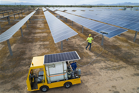 Jim Evans uses a solar-powered water pump on his electric wagon to clean an array near Tucson.
